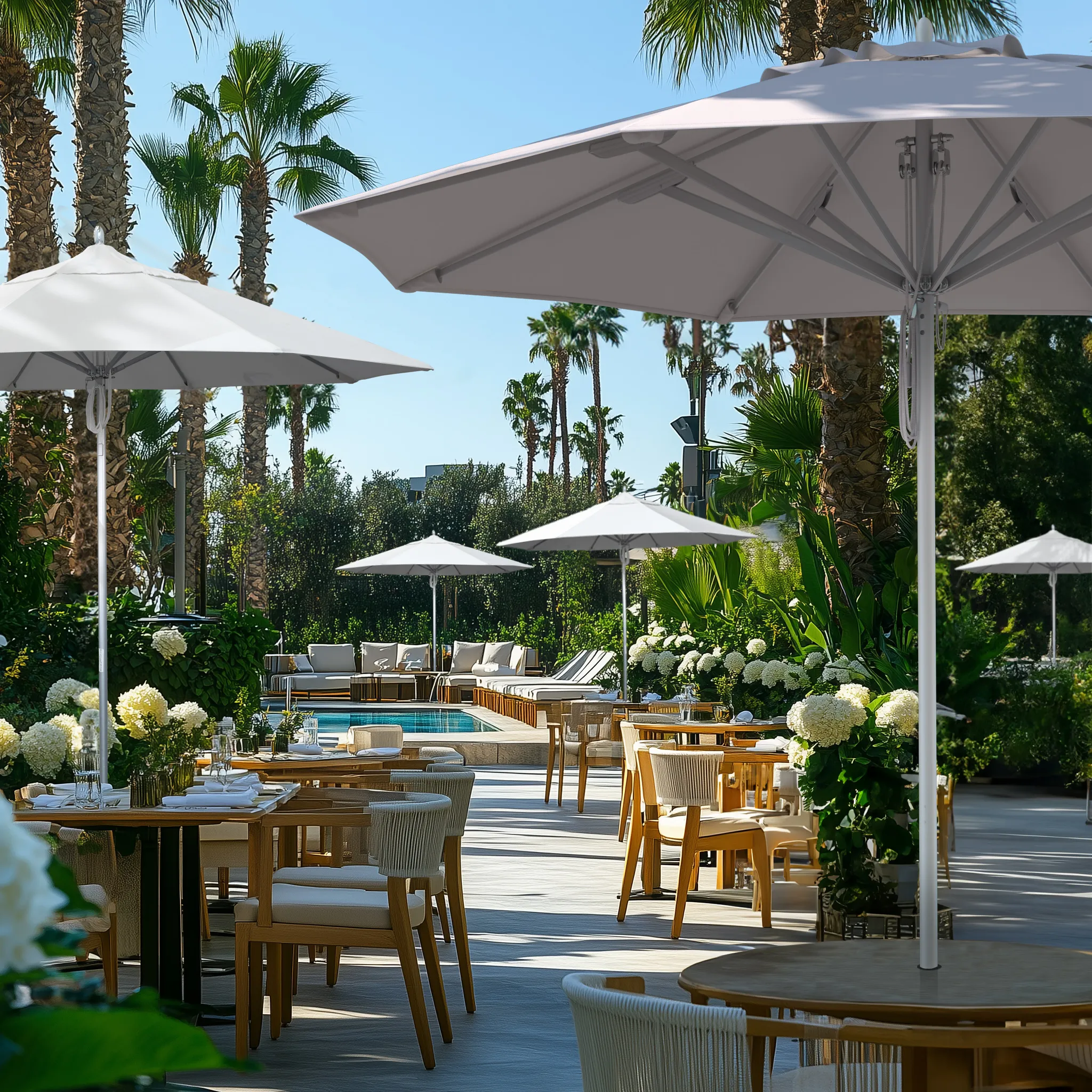 Showcasing the commercial-grade durability of the Newport Series patio umbrellas by California Umbrella, featuring sturdy aluminum frames and sleek white canopies in an elegant poolside dining and lounge setting.