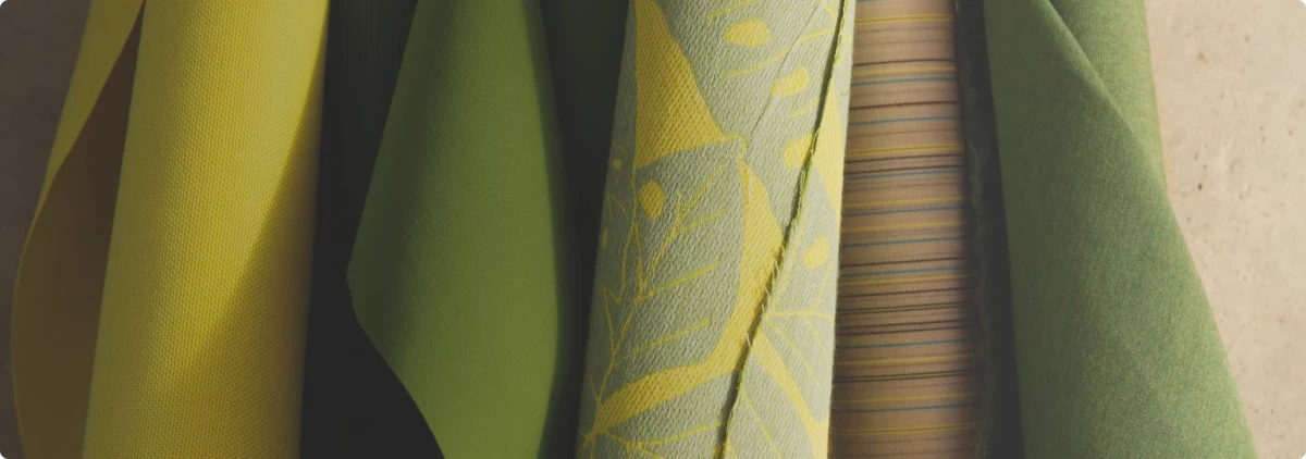 Close-up of premium outdoor umbrella fabrics in various shades of yellow and green, showcasing high-quality Sunbrella textiles for durability and style. Featuring intricate weaves and bold patterns, these fabrics offer versatile customization options for patio umbrellas and outdoor living spaces.